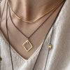 Diamond shaped, open frame pendant in 18K gold with a princess cut diamond on silver chain by Ayesha Mayadas