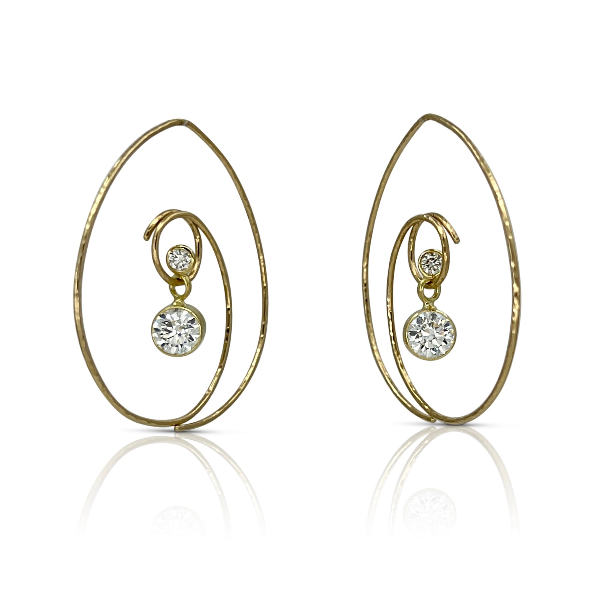 Spiral earrings in 18K yellow gold with a duo of dangling natural and lab grown diamonds shown on model made by Ayesha Mayadas
