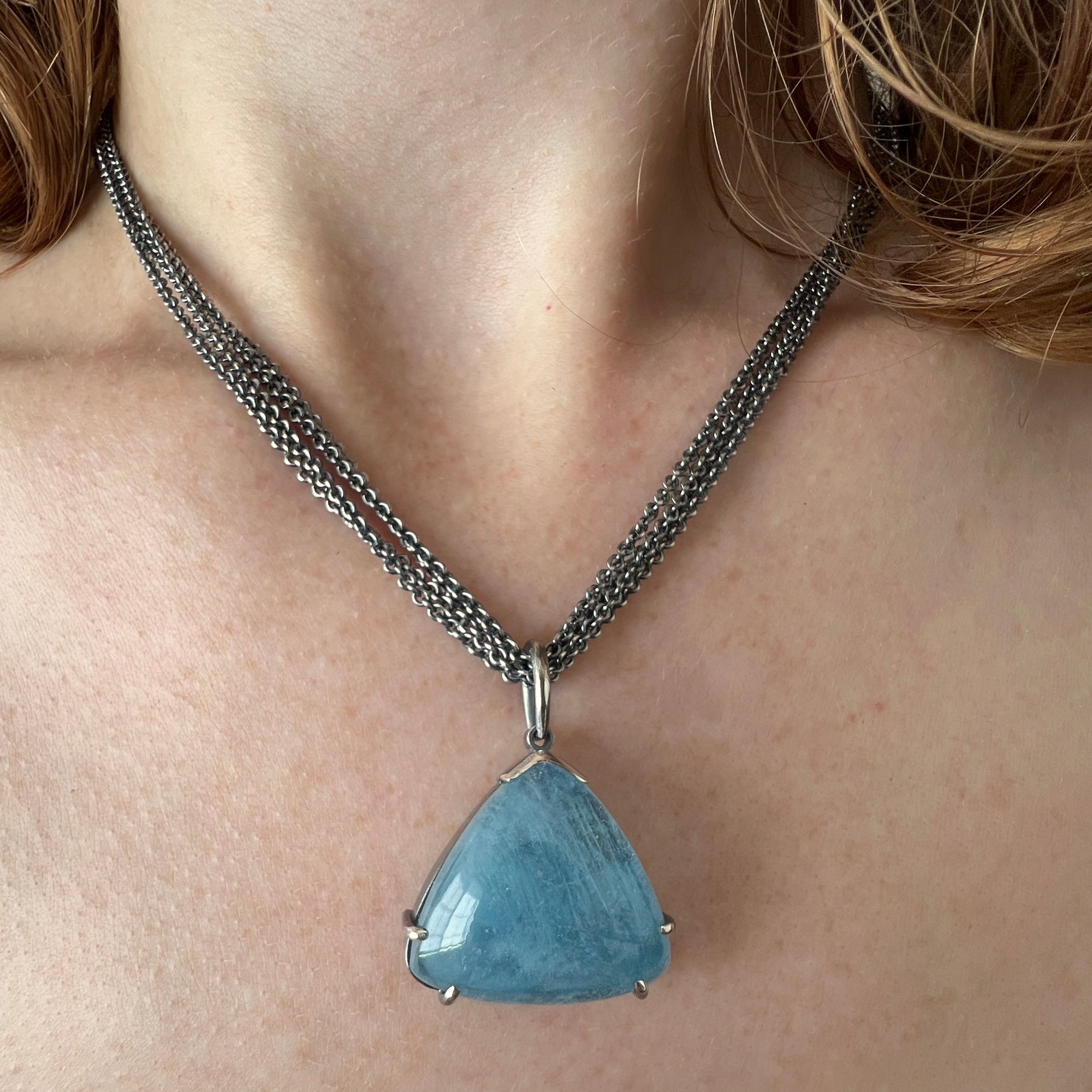 Necklace with large triangular aquamarine cabachon on multi sterling chain shown on model made by Ayesha Mayadas