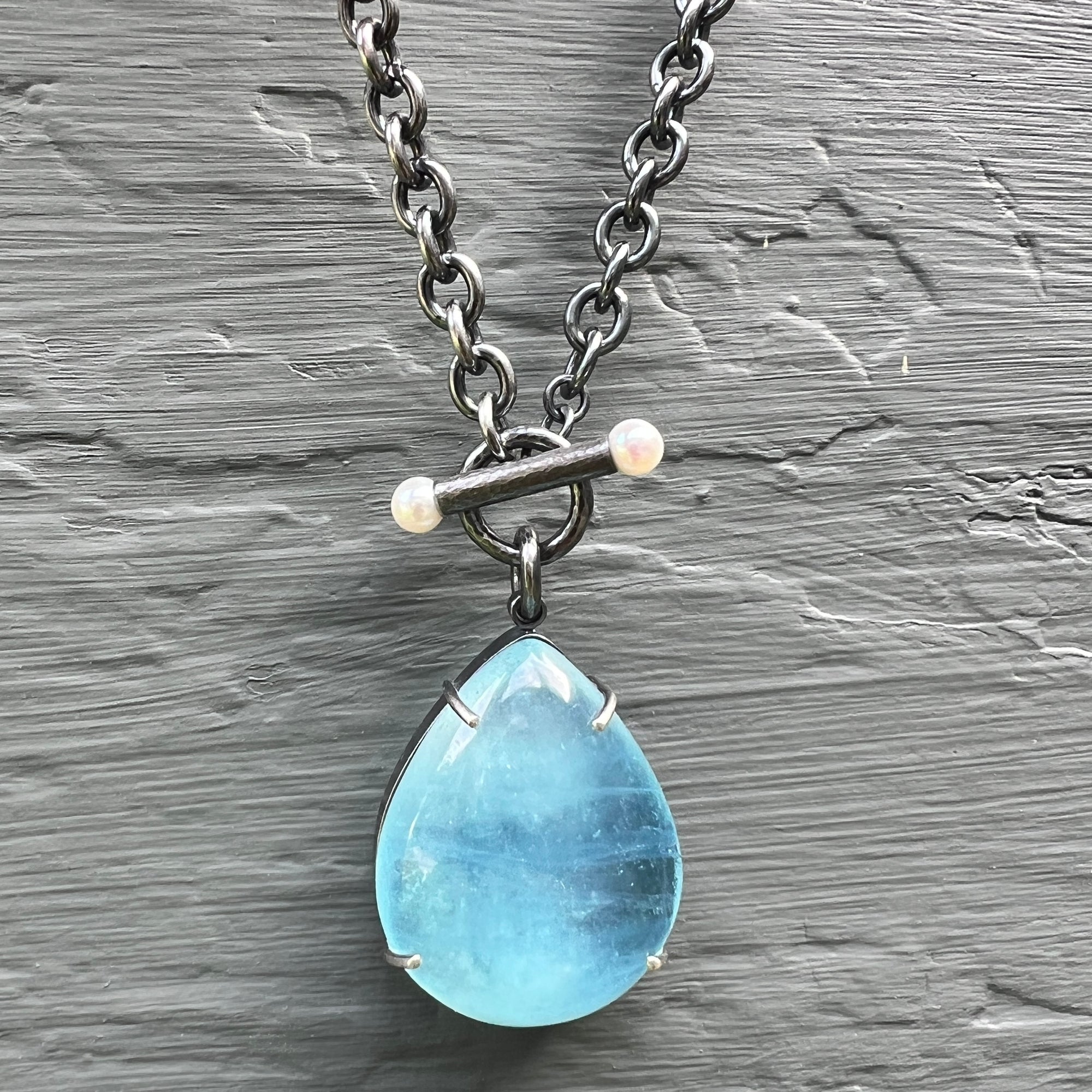 A luminescent aquamarine on a cable chain with a pearl accented toggle