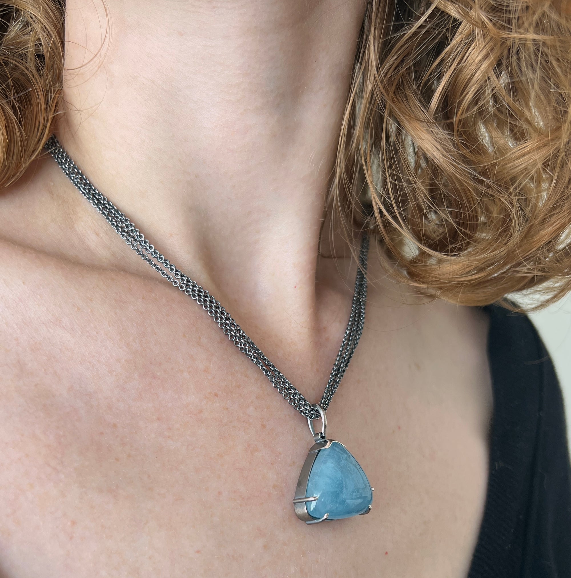 Necklace with large triangular aquamarine cabachon on multi sterling chain shown on model made by Ayesha Mayadas
