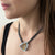 Necklace by Ayesha Mayadas 
with a triangular rutilated quartz pendant worn by a person 