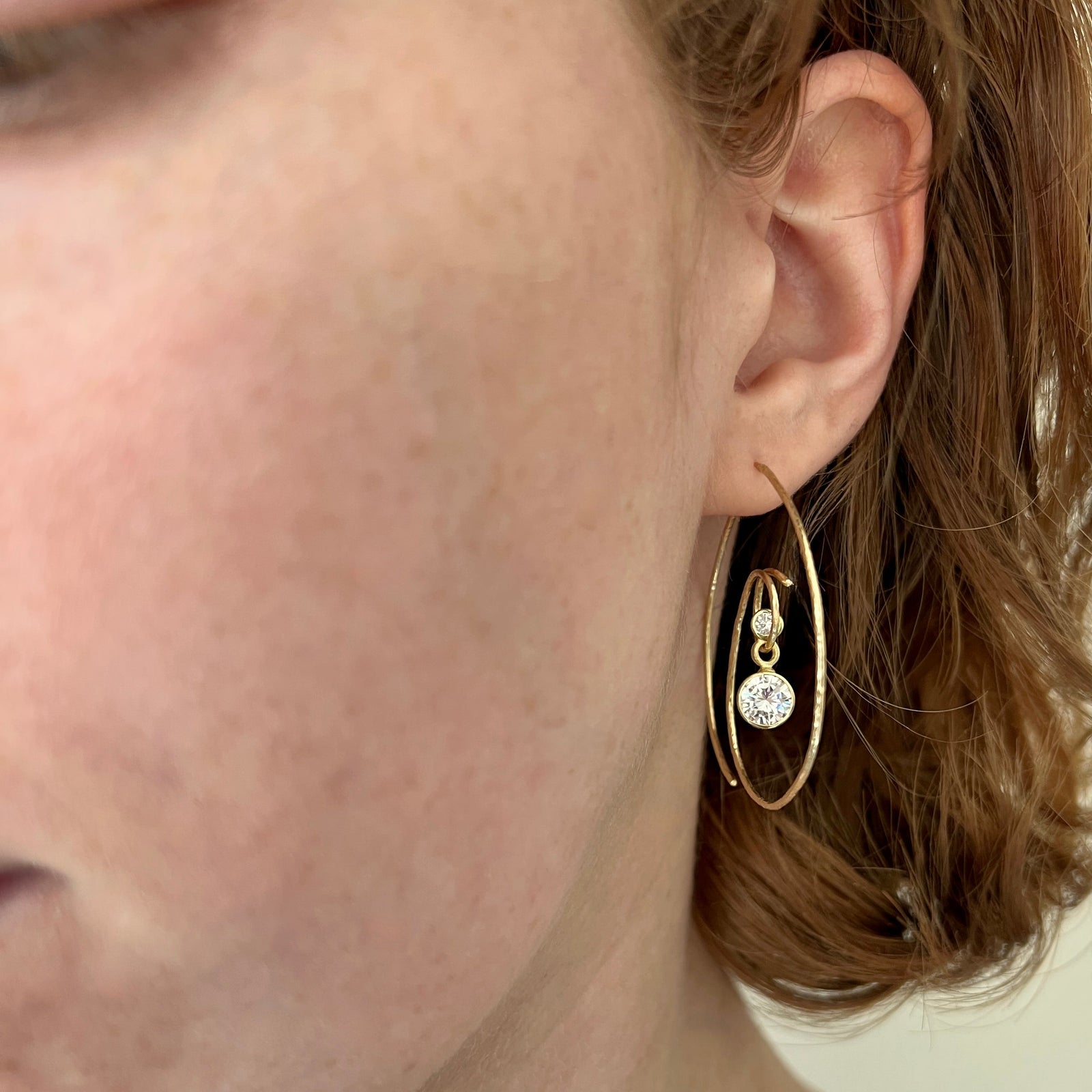 hoop earrings in 18K yellow gold with a duo of dangling natural diamonds and moissanite shown on model made by Ayesha Mayadas