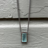 A dynamic, emerald-cut aquamarine pendant on long sterling chain
