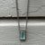 A dynamic, emerald-cut aquamarine pendant on long sterling chain