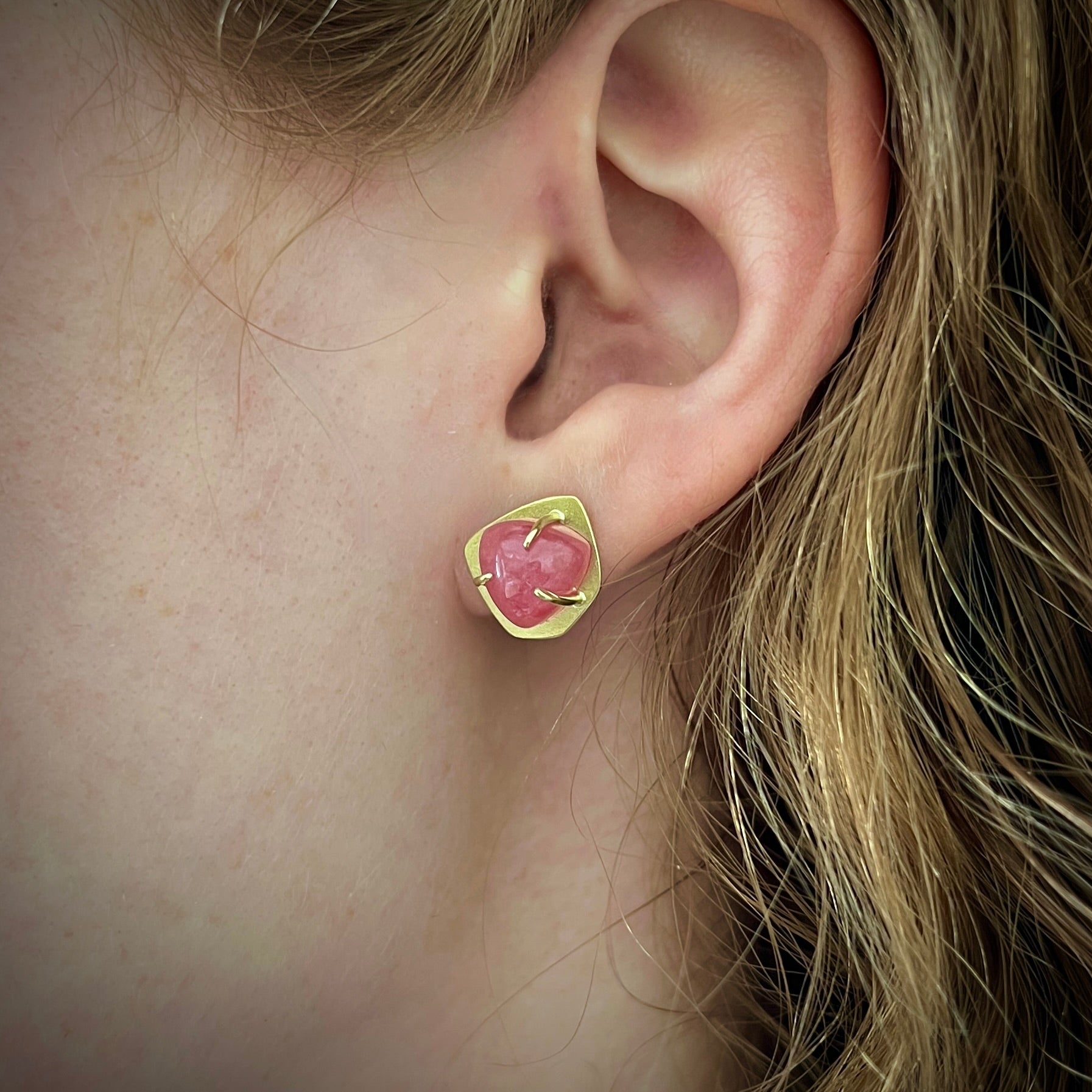 Earring studs with rose colored rhodochrosite in 18K yellow gold setting and post shown on model made by Ayesha Mayadas