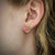 Earring studs with rose colored rhodochrosite in 18K yellow gold setting and post shown on model made by Ayesha Mayadas