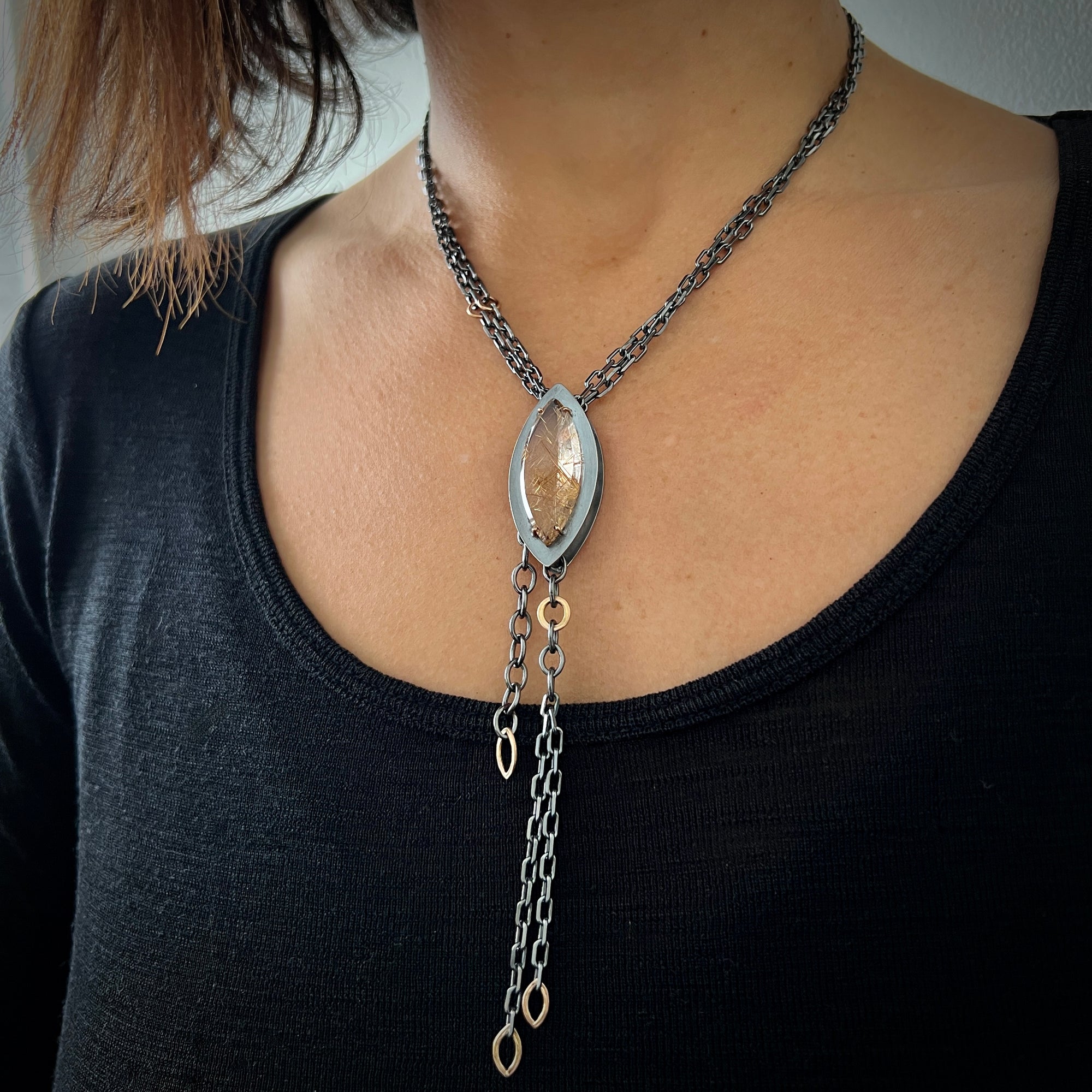 Necklace with large Marquis shaped rutilated quartz in sterling and rose gold on a multi sterling chain shown on model made by Ayesha Mayadas