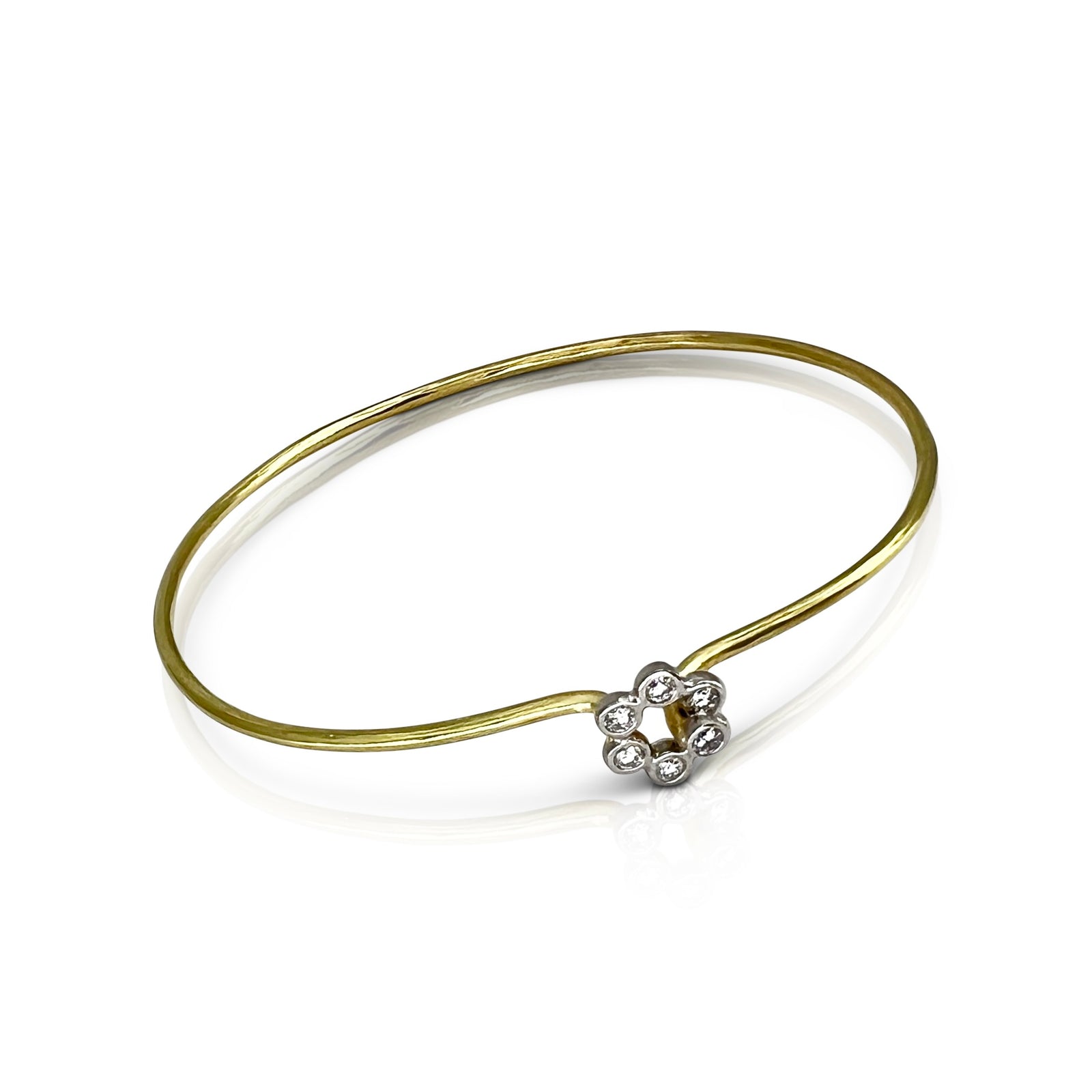 Gold bangle with a silver floral clasp on a white background