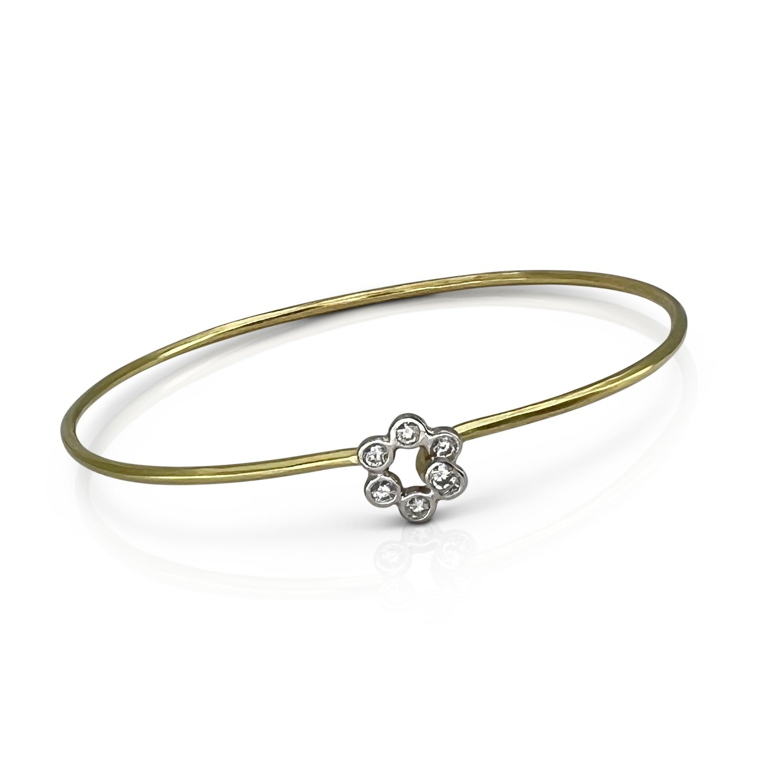 Gold bangle with a silver floral clasp on a white background