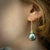 Slender, long, 18K yellow gold earrings with black Tahitian pearls on sculpted gold wires by Ayesha Mayadas
