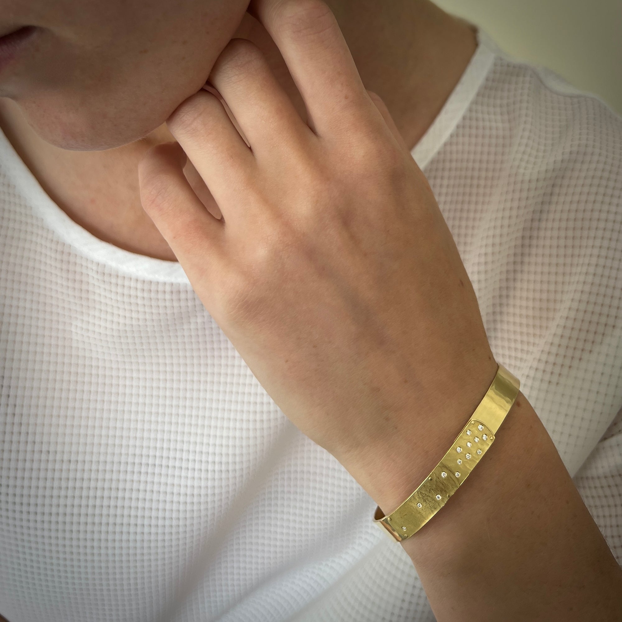 Stackable narrow cuff shown on model, forged and designed to close at the top just under the textured diamond studded tab. Bracelet is weighted to the bottom so it won&#39;t turn. 18K yellow gold, approx 7.5mm wide, 0.15 ct tw diamonds by Ayesha Mayadas