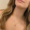18Kt and oval diamond pendant in an embrace motif or mother and child motif. Shown on a model.  Made by Ayesha Mayadas