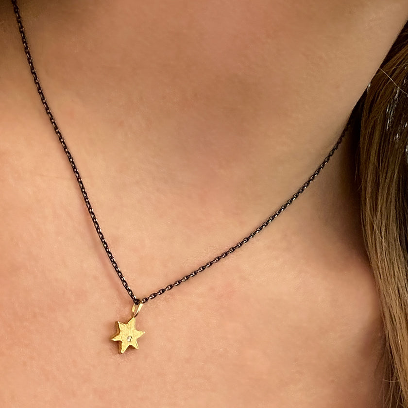 Star of David necklace in 18K yellow gold with a diamond and an oxidized sterling silver or 14K yellow gold cable chain shown on model by Ayesha Mayadas