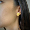 Round wafer stud earrings in sterling silver with an 18K yellow gold Vermeil finish shown on model by Ayesha Mayadas