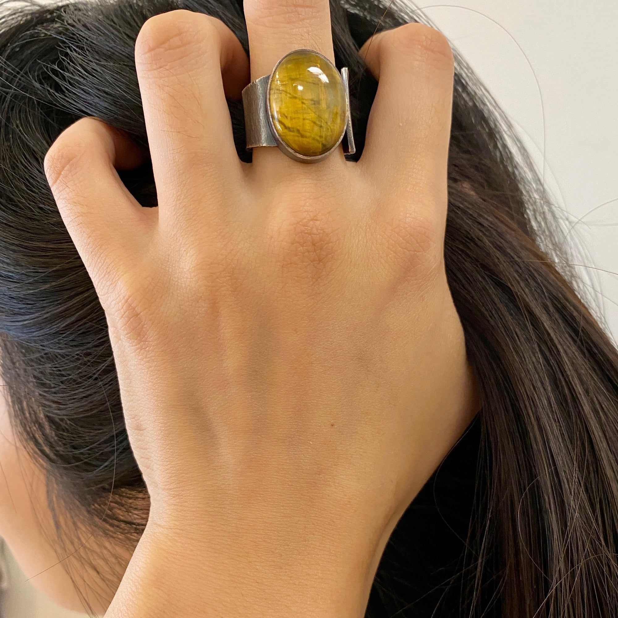 Wide oval shaped Nellite ring with a tiger's eye appearance in wafer textured sterling silver by Ayesha Mayadas