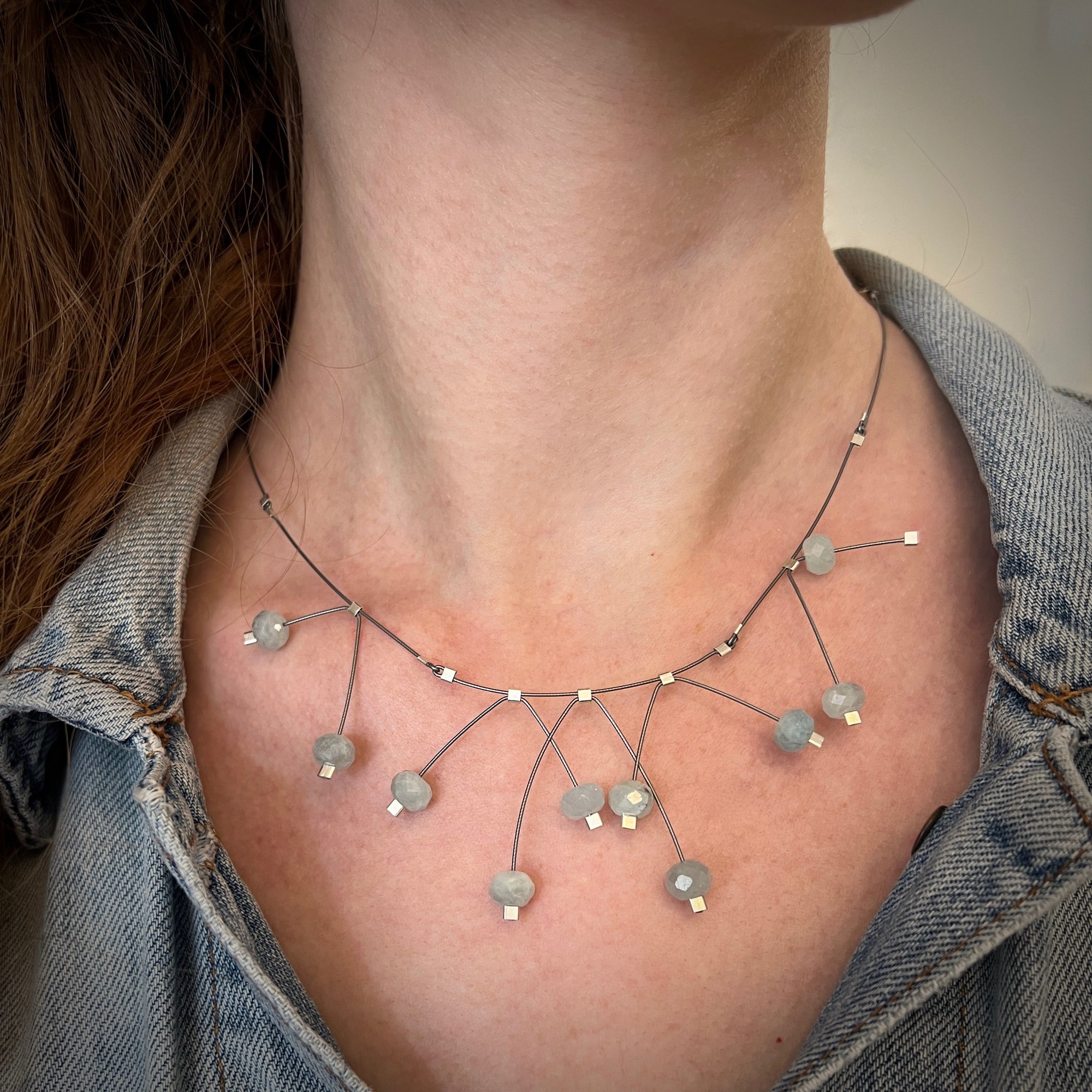 Aquamarine beads intersect each other on a gunmetal cable, 14K gold filled hardware, 16" by artist Meghan Patrice Riley