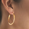 Off round forged Splash hoop earrings in Sterling Silver with 18K yellow gold Vermeil finish and barrel closure shown on model by Ayesha Mayadas